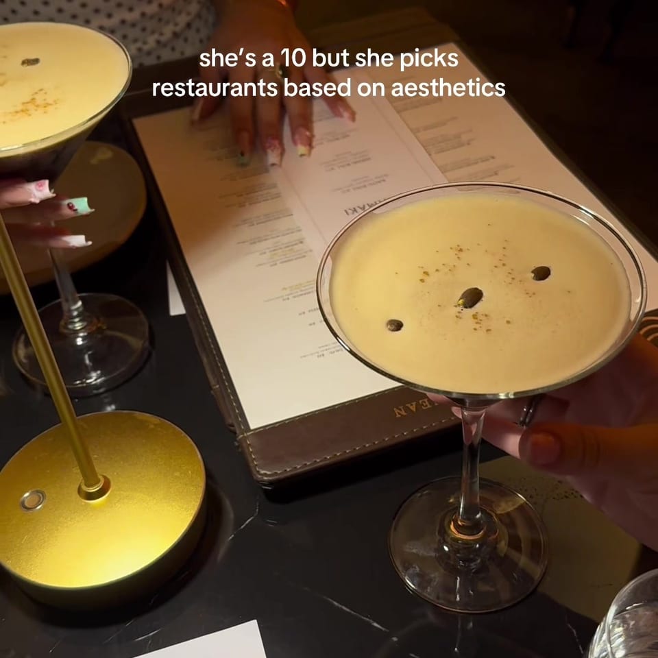 Restaurant table with two creamy cocktails, an open menu, gold table lamp, cutlery, and a Zoi Uramaki menu card.